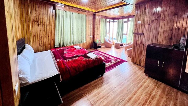 A wooden-paneled room with a bed, a wardrobe, and a seating area. - HOTEL TASHI GYAL TSEN (Gyalshing)