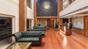 Un hall d’entrée spacieux, doté de canapés en cuir, d’un comptoir de réception et d’un grand lustre.