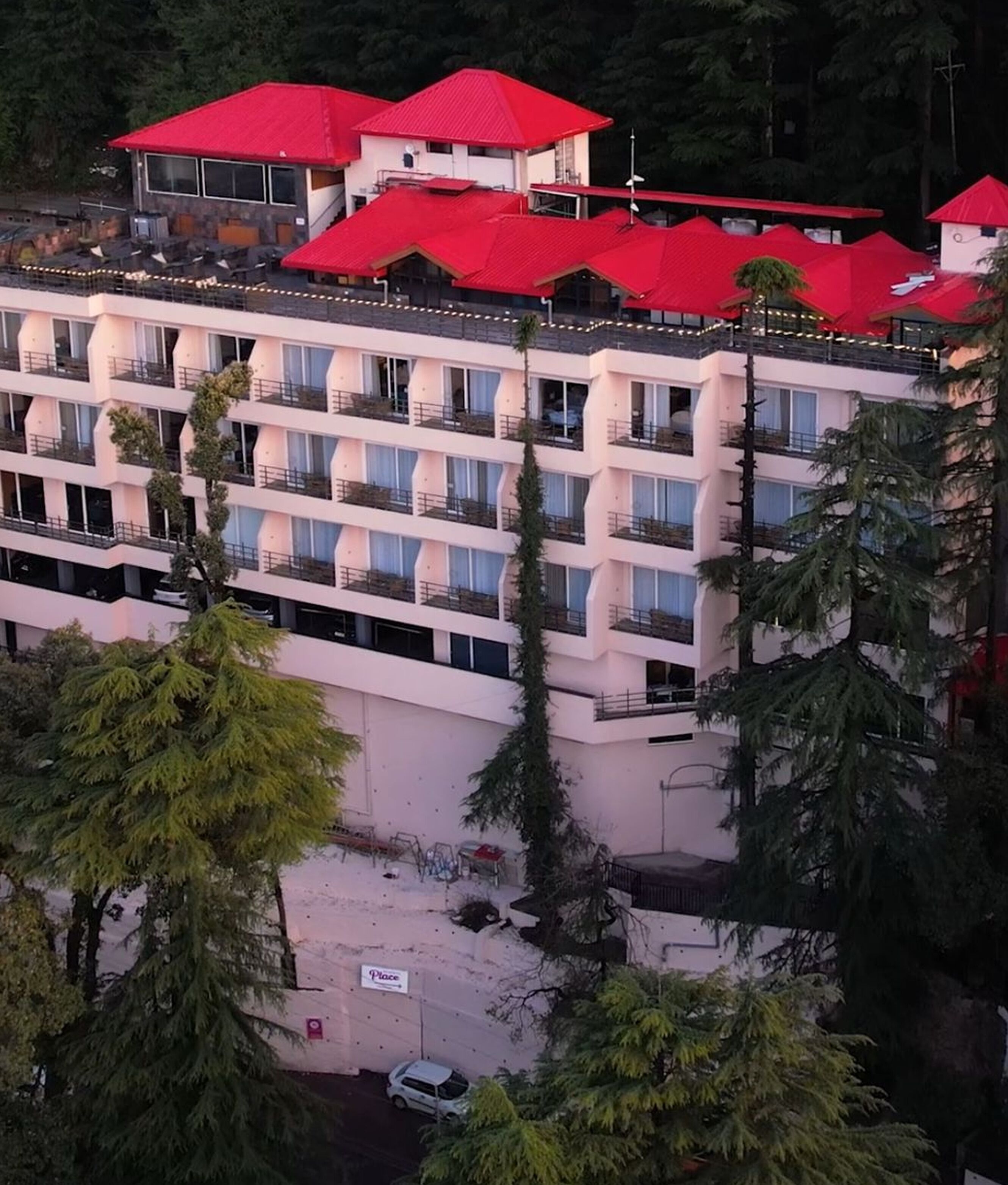 A multi-story hotel with red roofs and balconies, surrounded by trees.