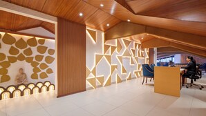 Un espace d’accueil moderne avec un plafond en bois, une statue de Bouddha et un mur décoratif lumineux aux motifs géométriques.