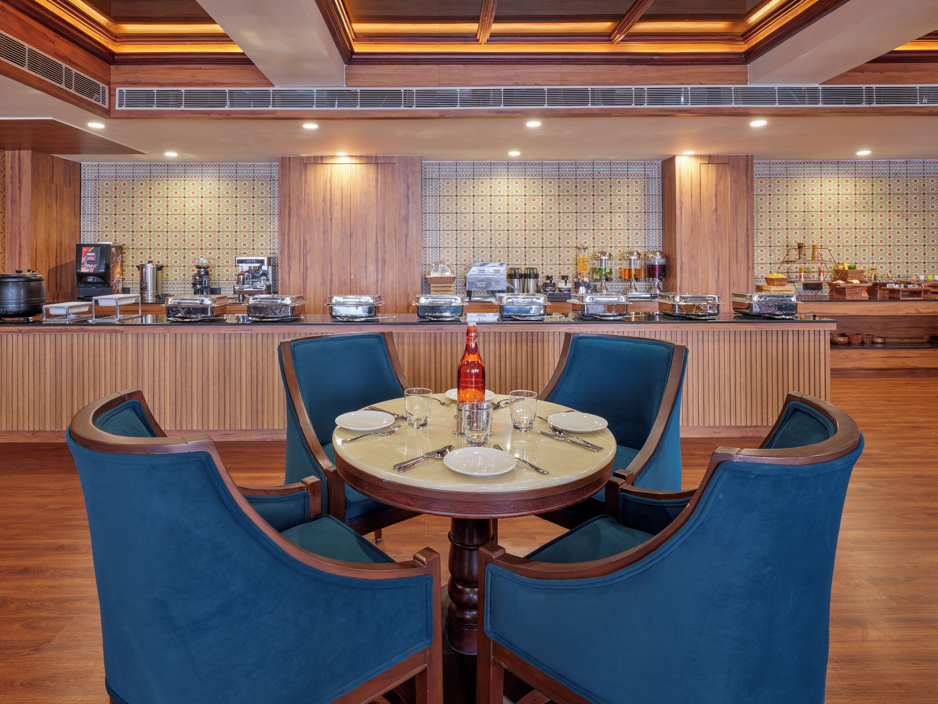Zona de bufé con una mesa redonda central para cuatro personas, rodeada de sillas tapizadas en azul.