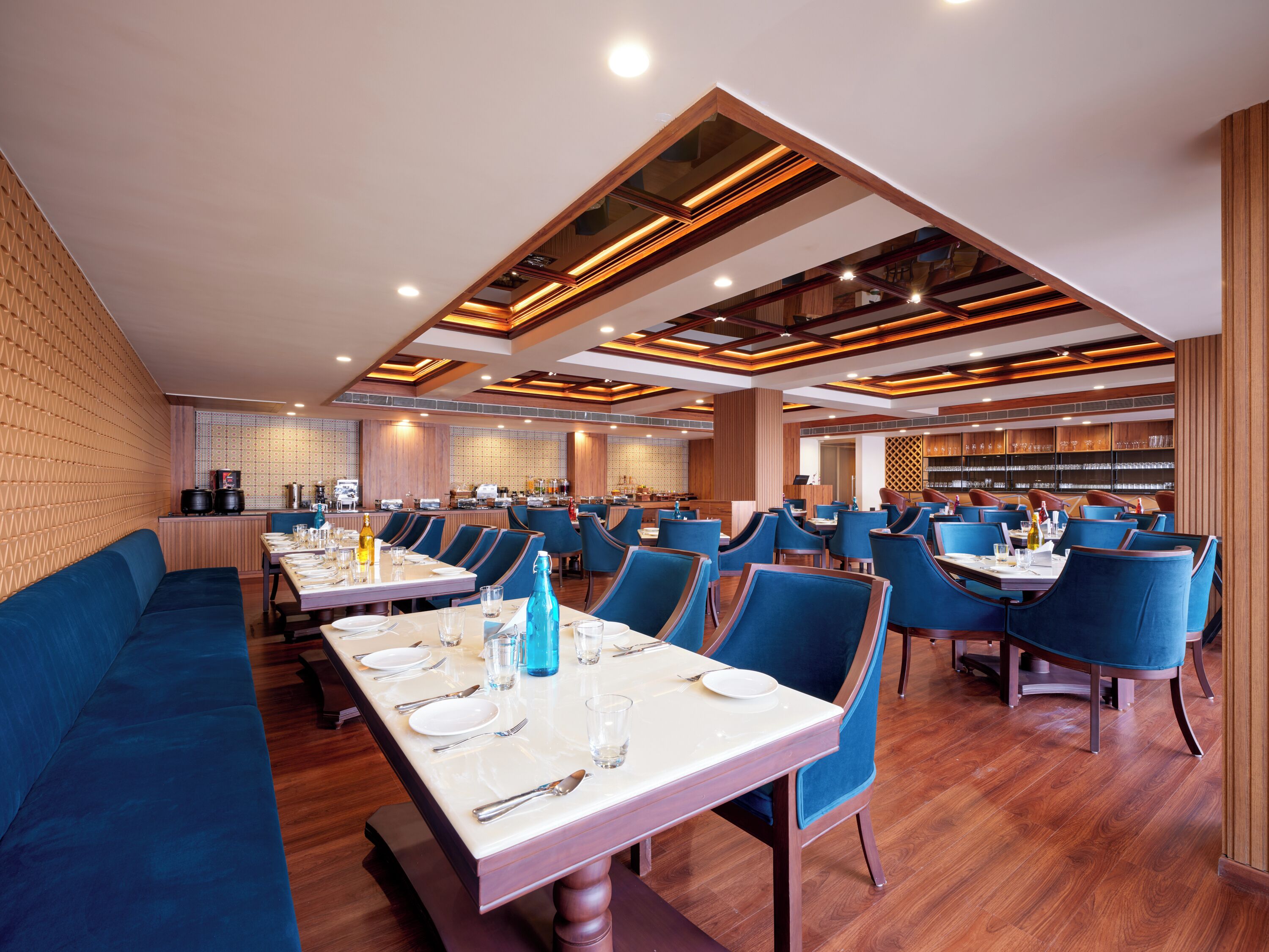 A spacious restaurant with high ceilings, modern lighting, and blue upholstered seating.