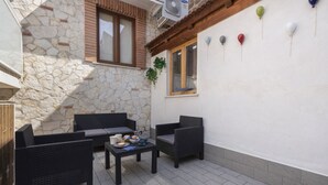 An outdoor patio with wicker furniture, a stone wall, and a window with shutters. - Two Bedrooms Apt in Sorrento Center with Terrace (Sorrento)