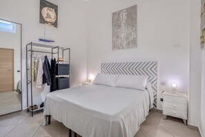 Ein Schlafzimmer mit einem Bett, einem Kleiderschrank, einem Nachttisch und einer Wand mit einem Chandelier.