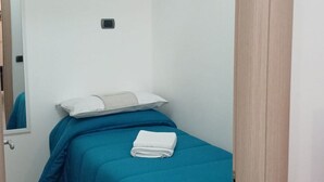 A small, single-bed room with a blue bedspread, a white pillow, and a folded white towel on the bed. - Two Bedrooms Apt in Sorrento Center with Terrace (Sorrento)
