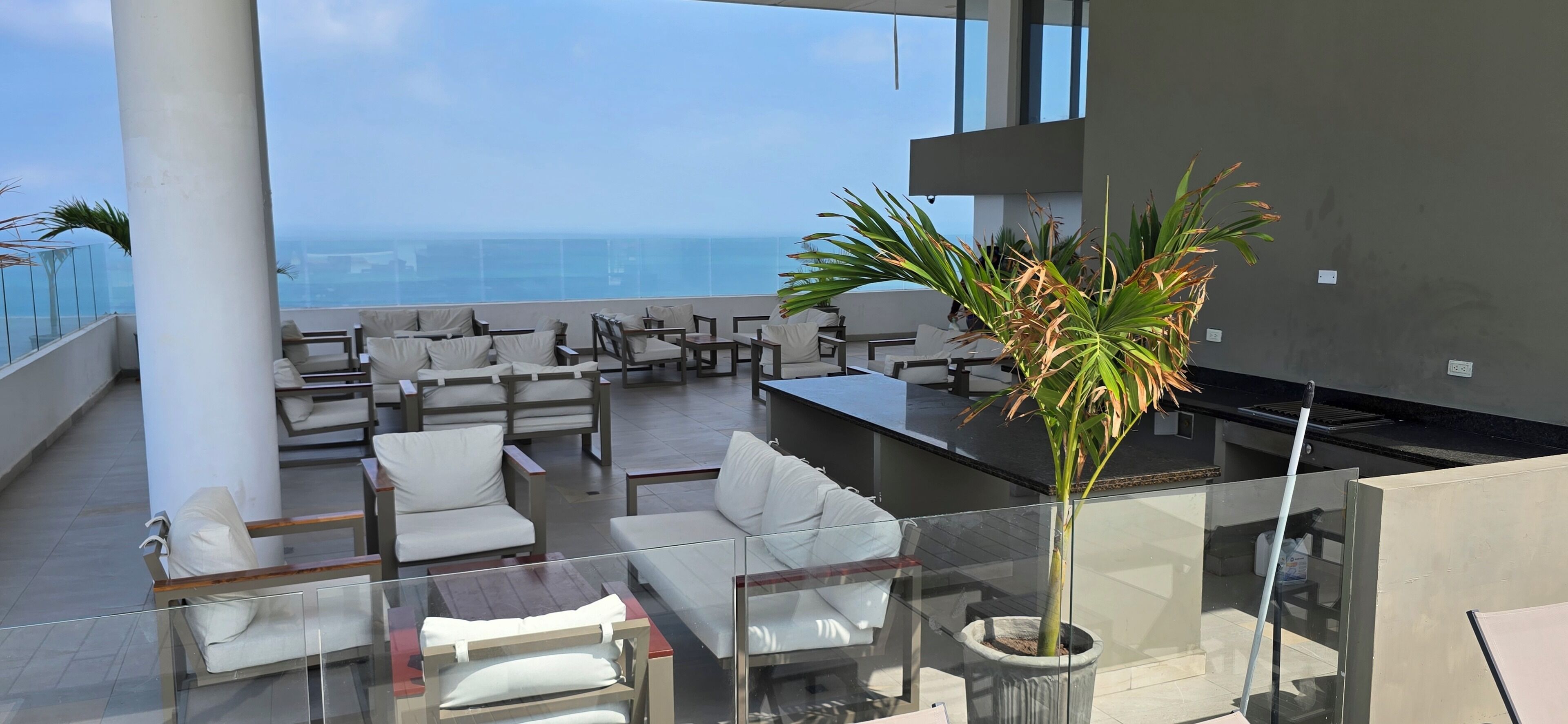 Um terraço com lounge e vista para o oceano, com móveis modernos e um vaso de planta.