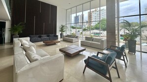 Eine großzügige Lobby im modernen Stil, mit einem großen Sitzbereich, Sofas, Sesseln, einem Couchtisch und Topfpflanzen.