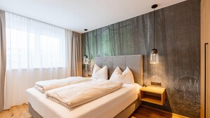 A modern bedroom with a large bed, a nightstand, and a wall-mounted lamp. - Modern apartment with balcony (Fiss)