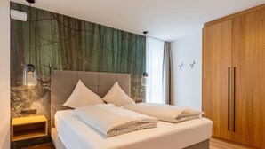 Een slaapkamer met een bed, een nachtkastje, een kledingkast en een muur met een bosreliëf.
