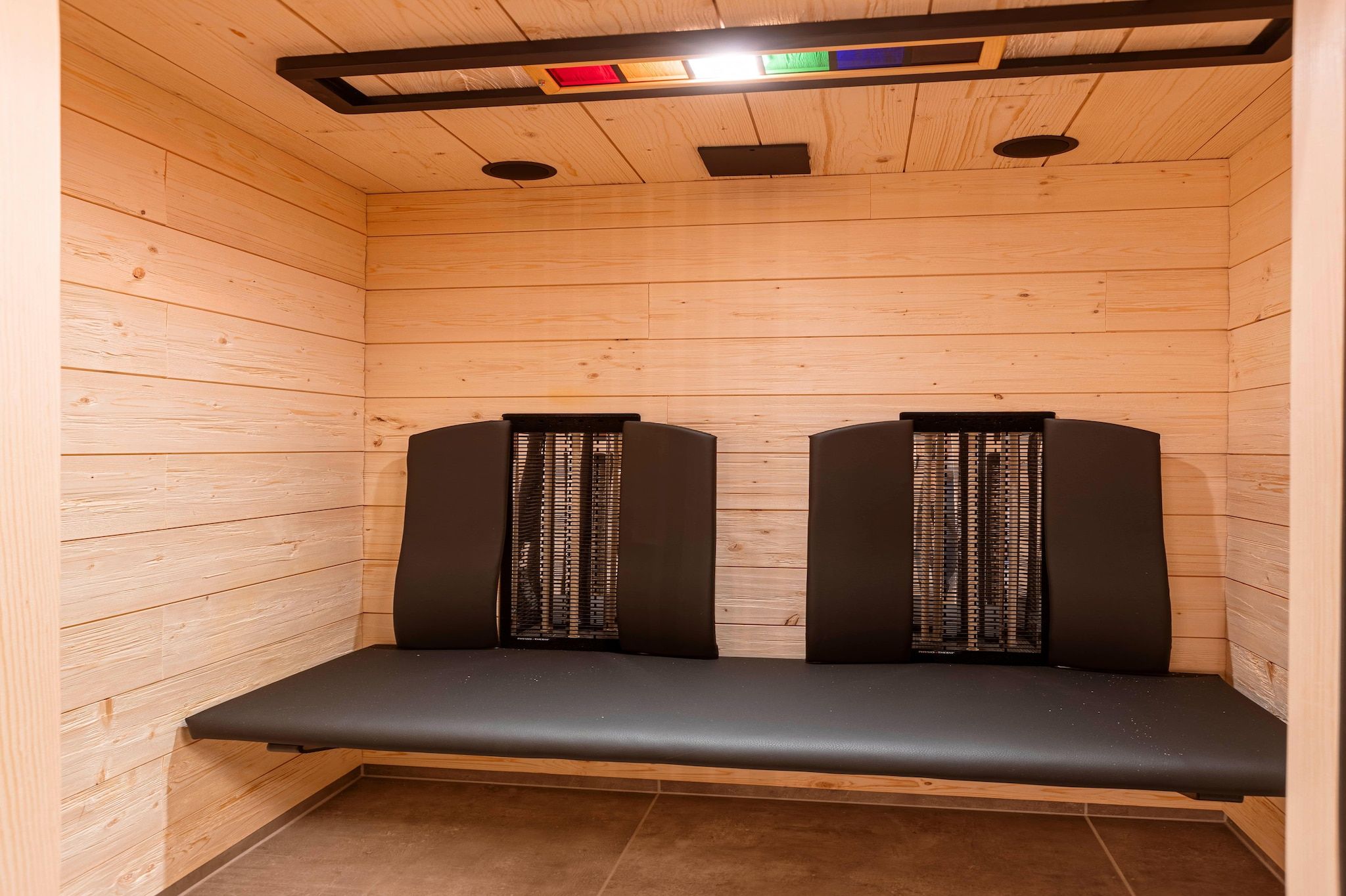 A sauna room with wooden walls and a bench.