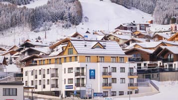 A hotel with multiple floors, a ski lift in the background, and snow-covered surroundings.
