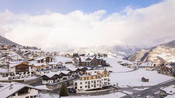 A snow-covered mountain town with chalet-style buildings, a main road, and a ski slope in the background.