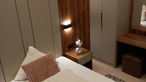 Un dormitorio moderno con cama, mesita de noche y velador con un florero.