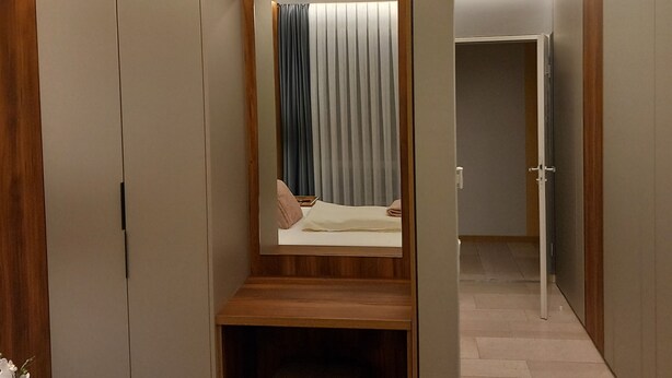 Una habitación de hotel moderna con escritorio integrado, espejo y armario.