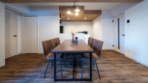 A dining area with a wooden table and chairs, a brick wall, and a ceiling with exposed beams.