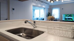 A modern kitchen with a stainless steel sink, a white countertop, and a hanging light fixture.