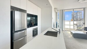 A modern kitchen with stainless steel appliances, a large window, and a balcony with a city view. - Bright Zetland Apartment with CBD Views and Fast Free WiFi (Zetland)