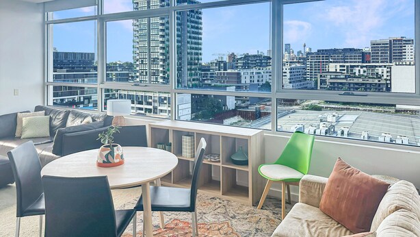 A modern living room with a large window, a round table, and a sofa. - Bright Zetland Apartment with CBD Views and Fast Free WiFi (Zetland)