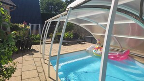 A covered swimming pool with a slide, surrounded by a patio area with outdoor furniture and a fenced garden. - Chic, cozy 35m² tepee with swimming pool in Pontacq near Lourdes. (Pontacq)
