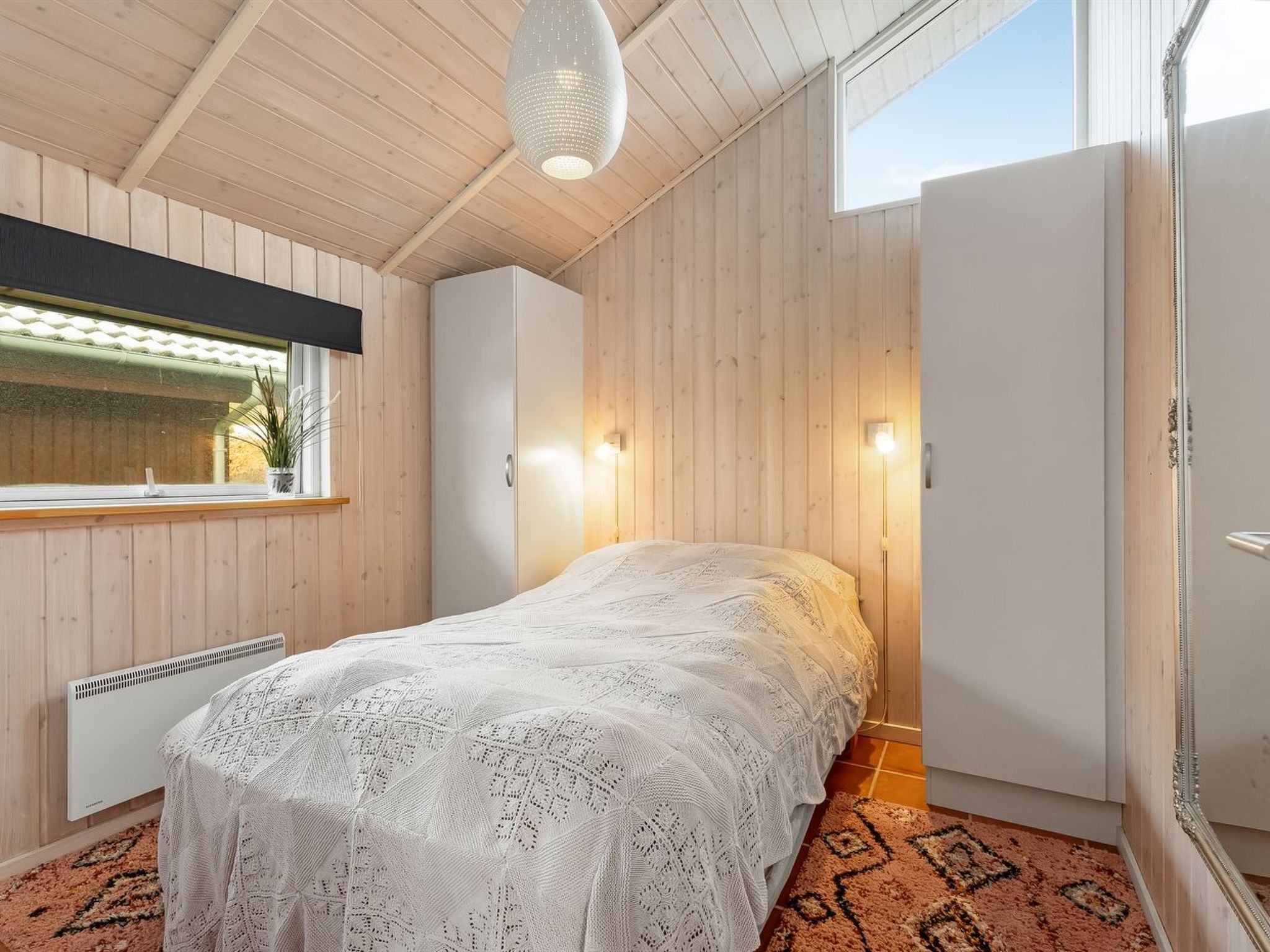 Une chambre à coucher avec un lit, une fenêtre, un radiateur et un luminaire au plafond.