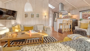Un vaste salon doté d’un plafond en bois, d’un coin repas et d’une cuisine.