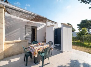 A patio with a table and chairs, a covered area, and a door leading to a covered space. - Villa Acqua Azzurra with Private Parking and Air Conditioning (Torre Lapillo)