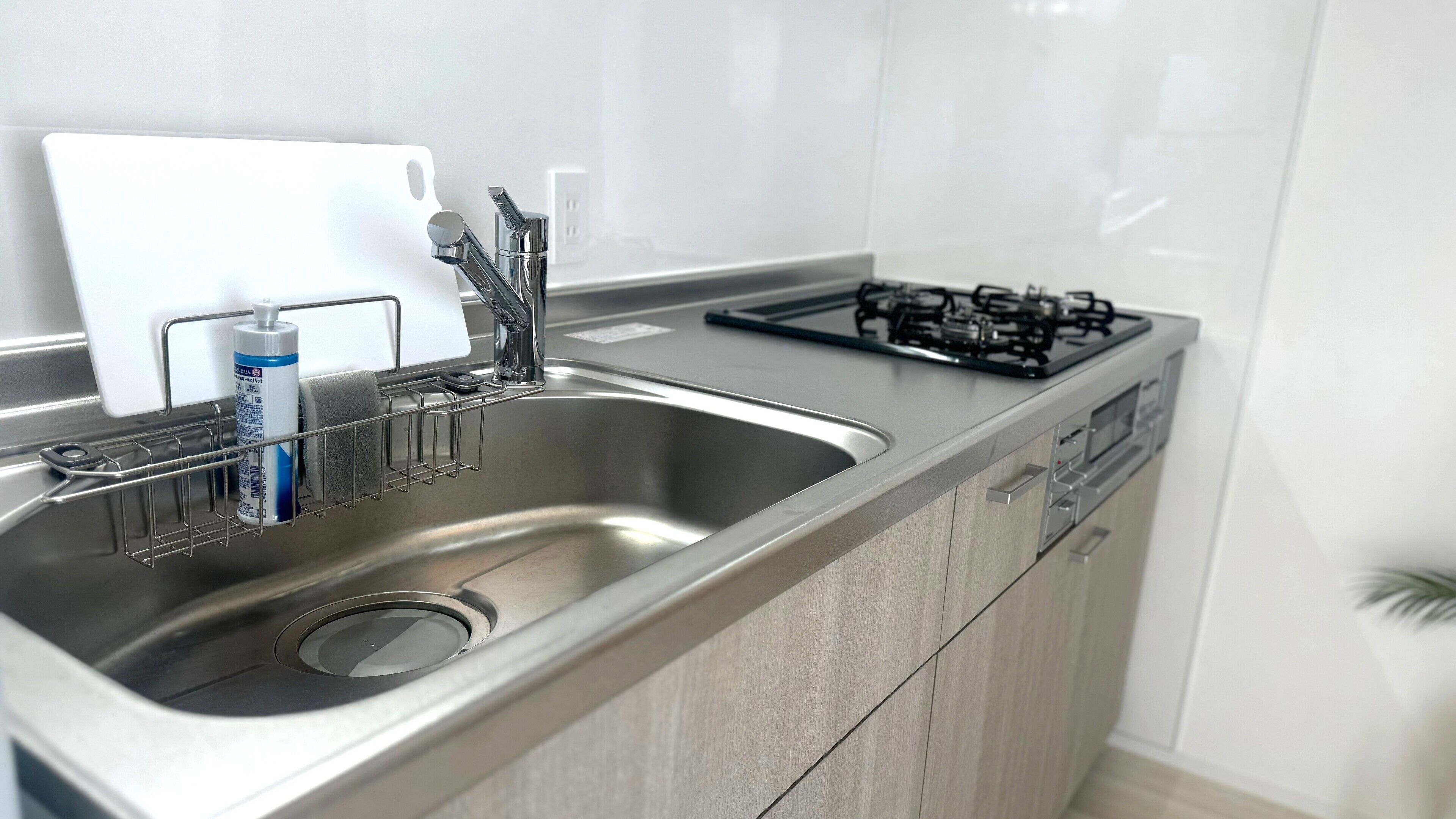 A modern kitchen with a stainless steel sink, a gas stove, and a dish rack.