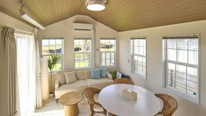 A spacious living room with a high ceiling, large windows, a beige sofa, a round table, and wicker chairs. - Solana Shirahama (Minamiboso)