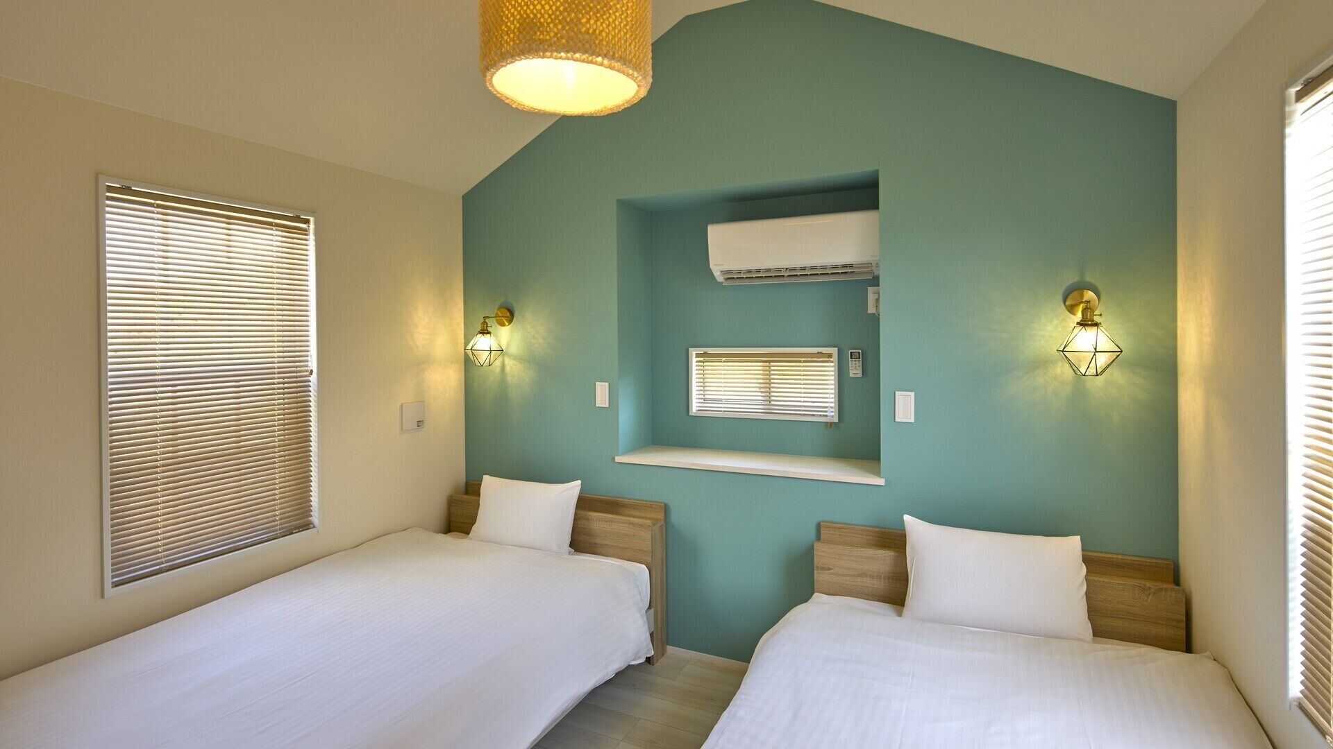 A bedroom with two beds, teal walls, and a built-in air conditioning unit.