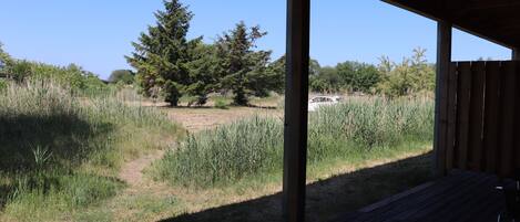 A covered outdoor area with a view of a grassy field and trees.