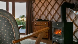 A cozy room with a wood-burning stove, a wooden dresser, and a chair. - Halbinsel Peenemünde (Peenemünde)