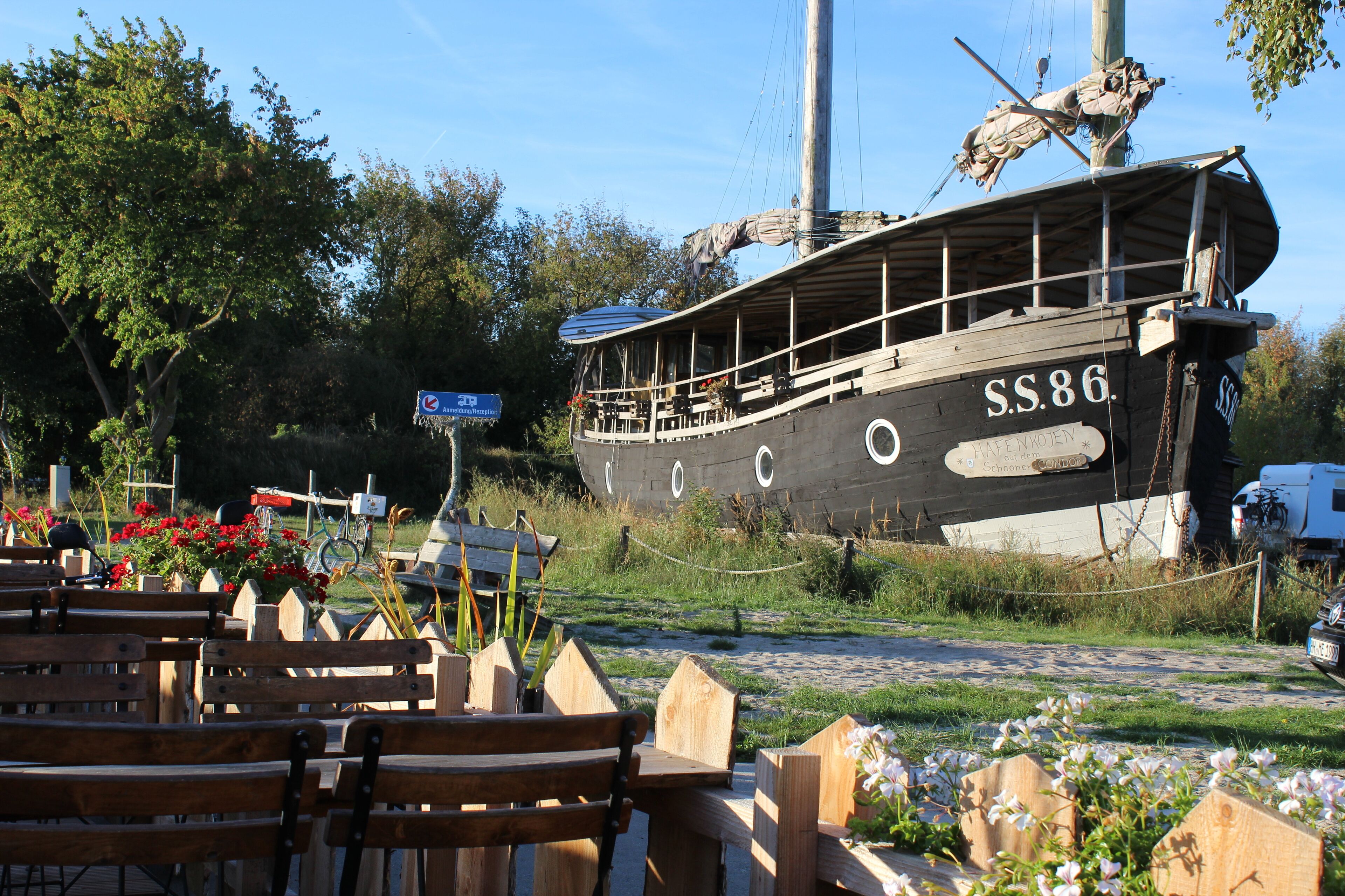 Un bote de madera con el número SS.86, rodeado de bancos de madera y flores.