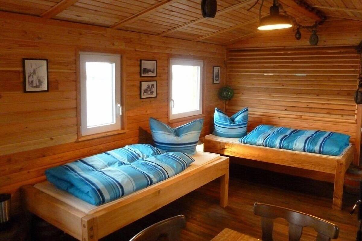 A cabin with two wooden benches, wooden walls, and a sloped ceiling.