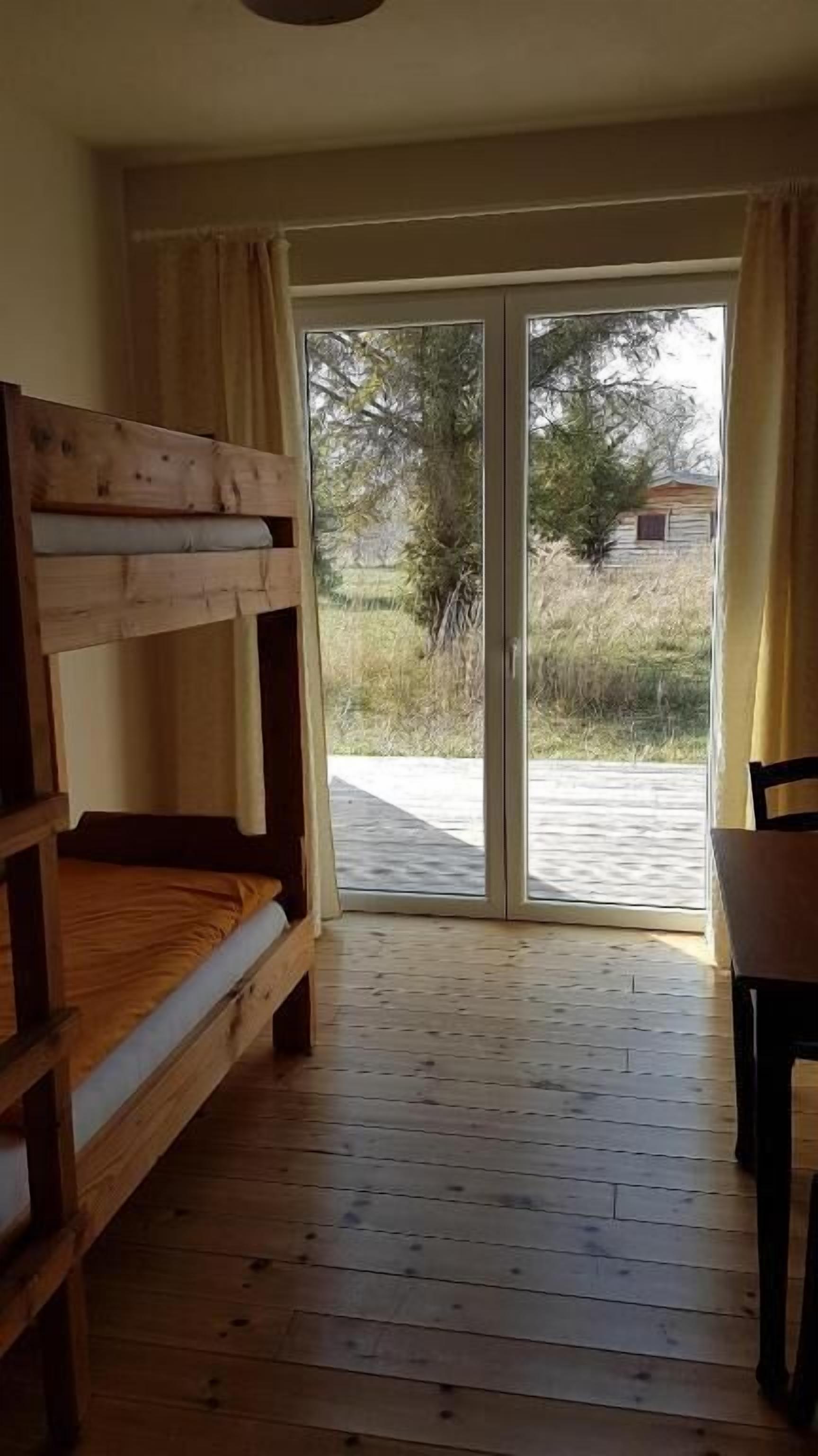 Ein Zimmer mit Etagenbett, einem Sessel und einer Schiebetür zu einem Außenbereich.