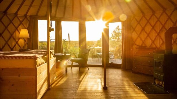 A cozy room with a bed, a chair, a table, and a dresser, with a large window allowing natural light and a view of the outdoors. - Halbinsel Peenemünde (Peenemünde)