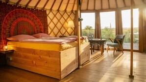 A cozy, wooden interior of a yurt with a bed, a table, and chairs. - Halbinsel Peenemünde (Peenemünde)