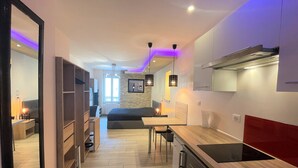 A modern kitchen with a built-in oven, a dining area with a table and chairs, and a large mirror on the left.