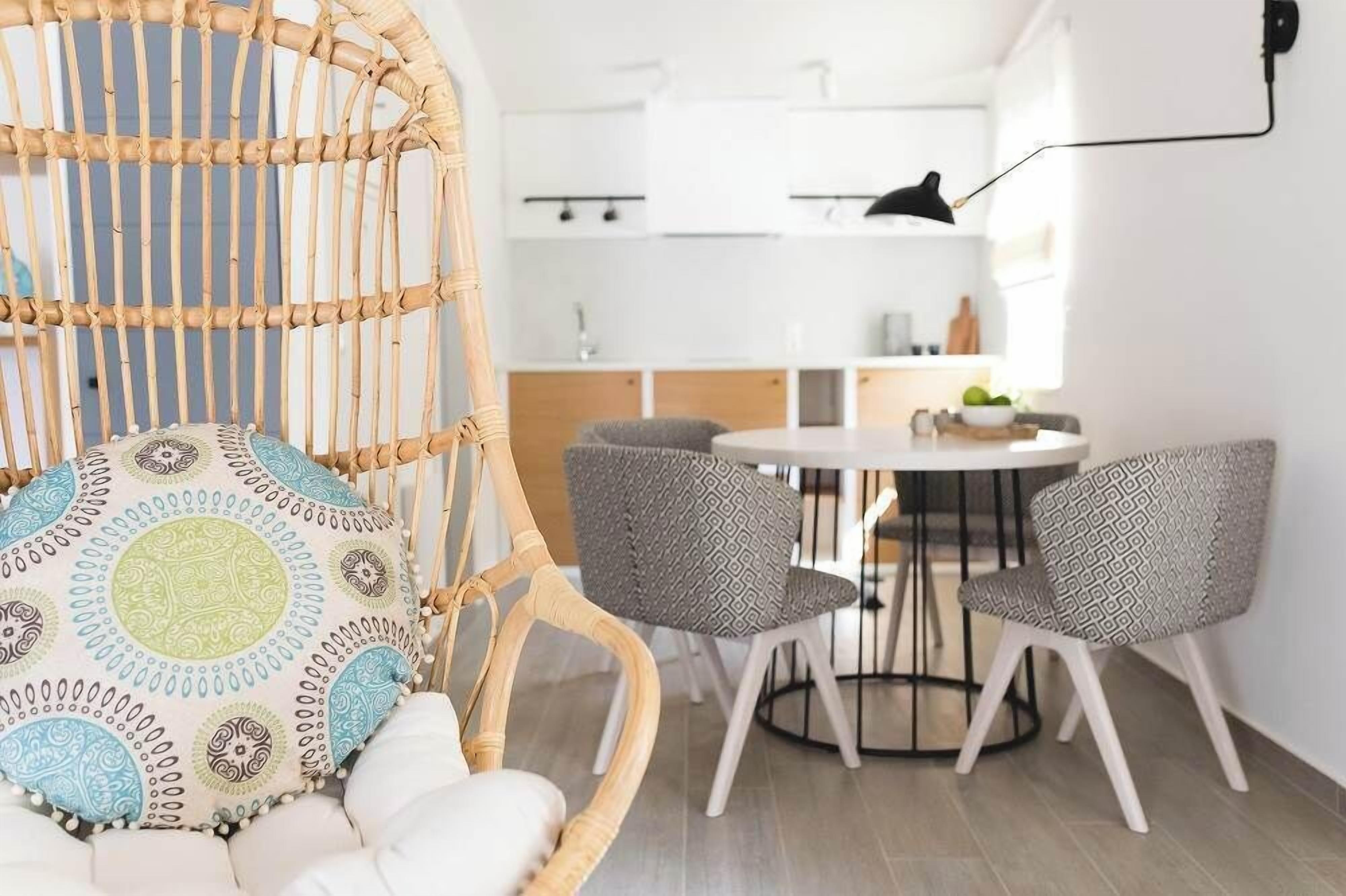A modern kitchen with white cabinets, a round dining table, and two patterned chairs.