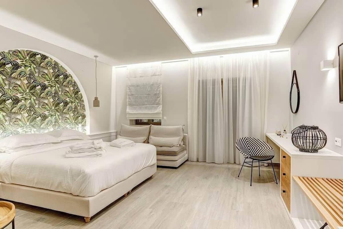 A modern bedroom with a bed, a seating area, and a desk.