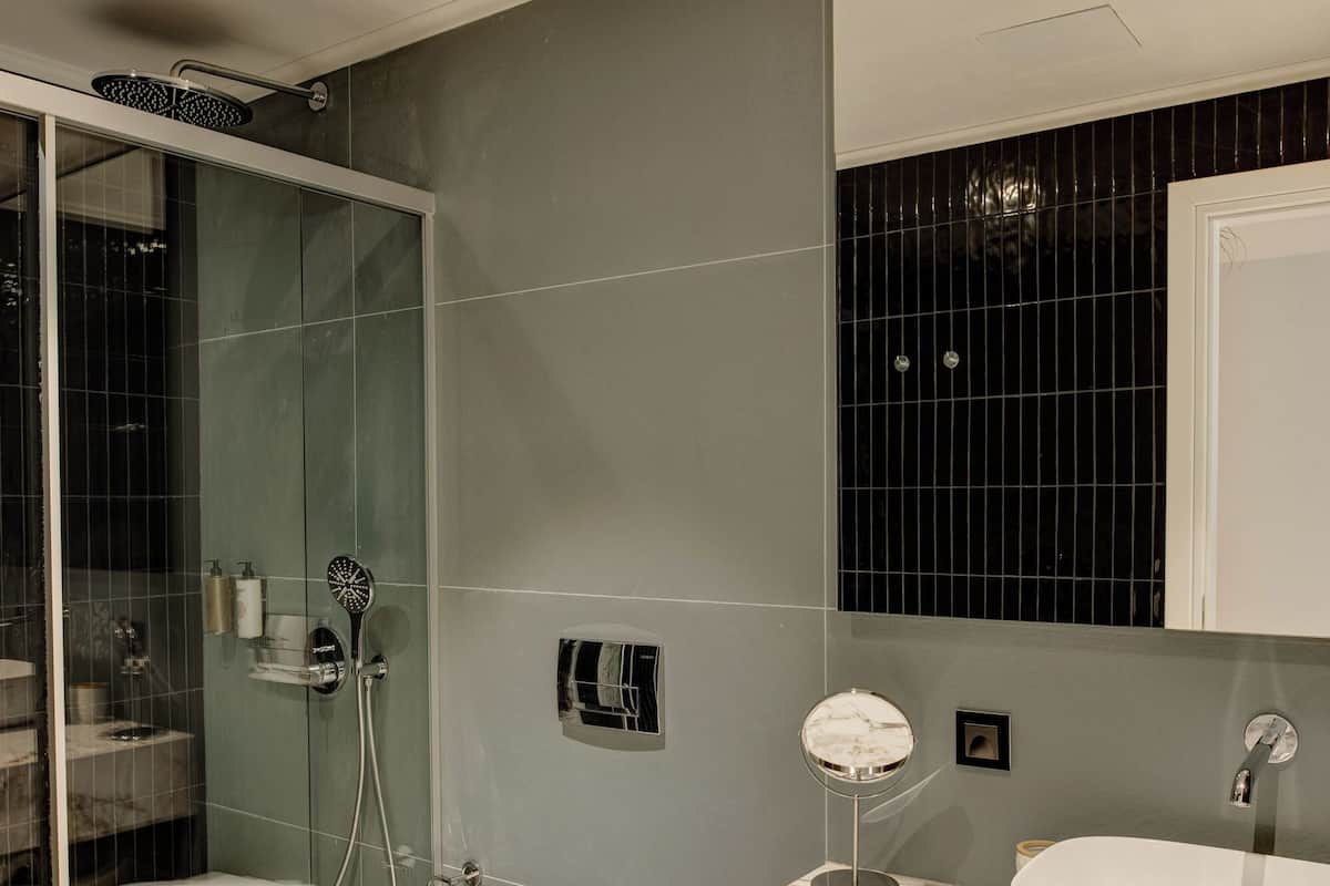 A modern bathroom with a glass-enclosed shower, a white toilet, and a marble vanity with two sinks.