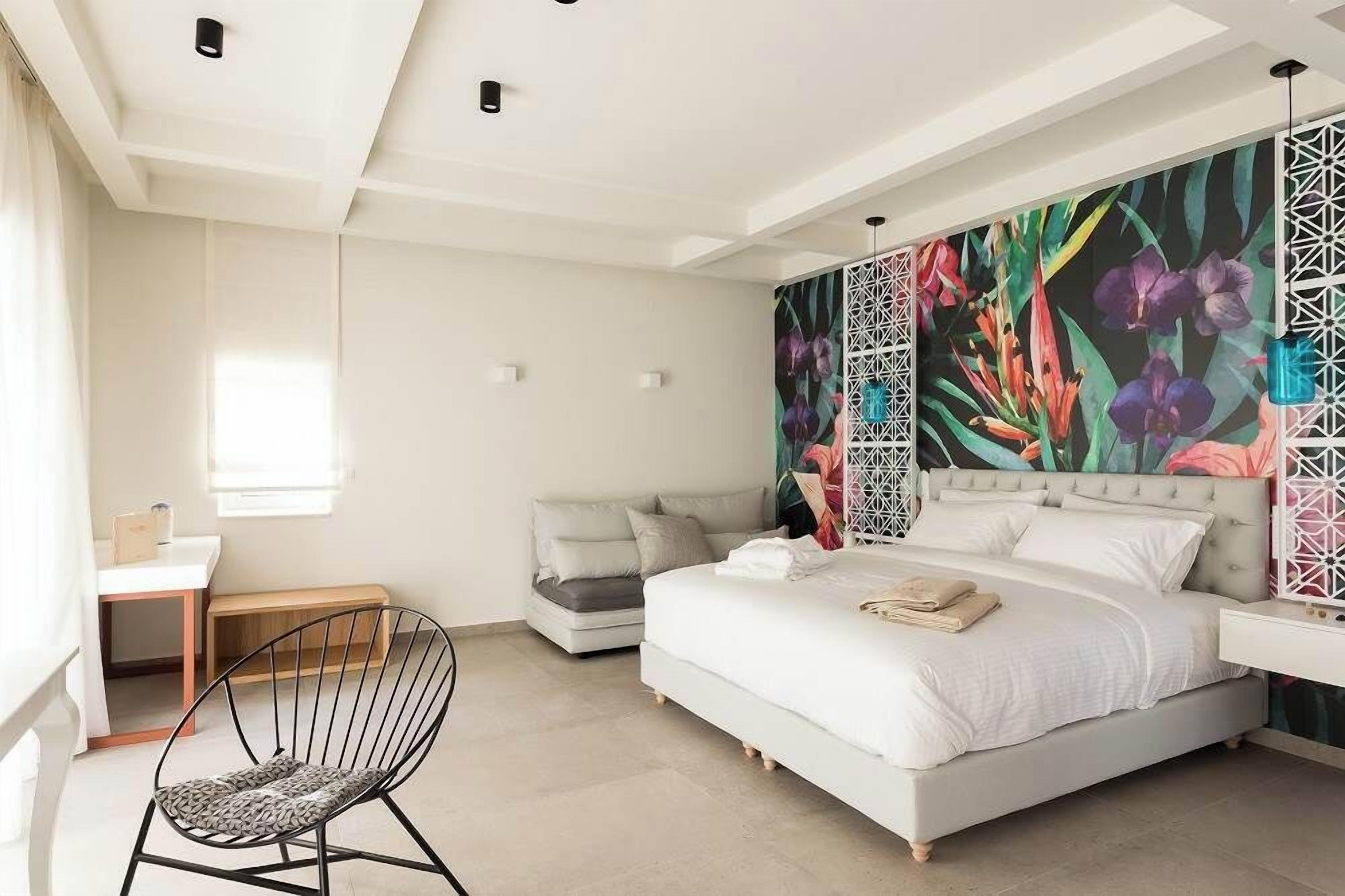 A bedroom with a bed, a desk, a chair, and a window.