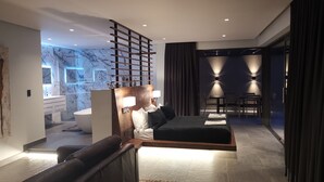 Habitació d'hotel moderna amb un llit gran, zona de seients i espai de dinar separat.