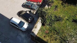 Un parking avec plusieurs voitures garées, un bâtiment dont l’entrée est visible, et quelques espaces verts.