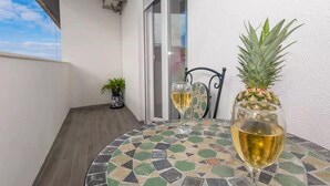 Une table ronde ornée d’un motif de mosaïque, deux verres de vin blanc et un ananas posés sur la table.