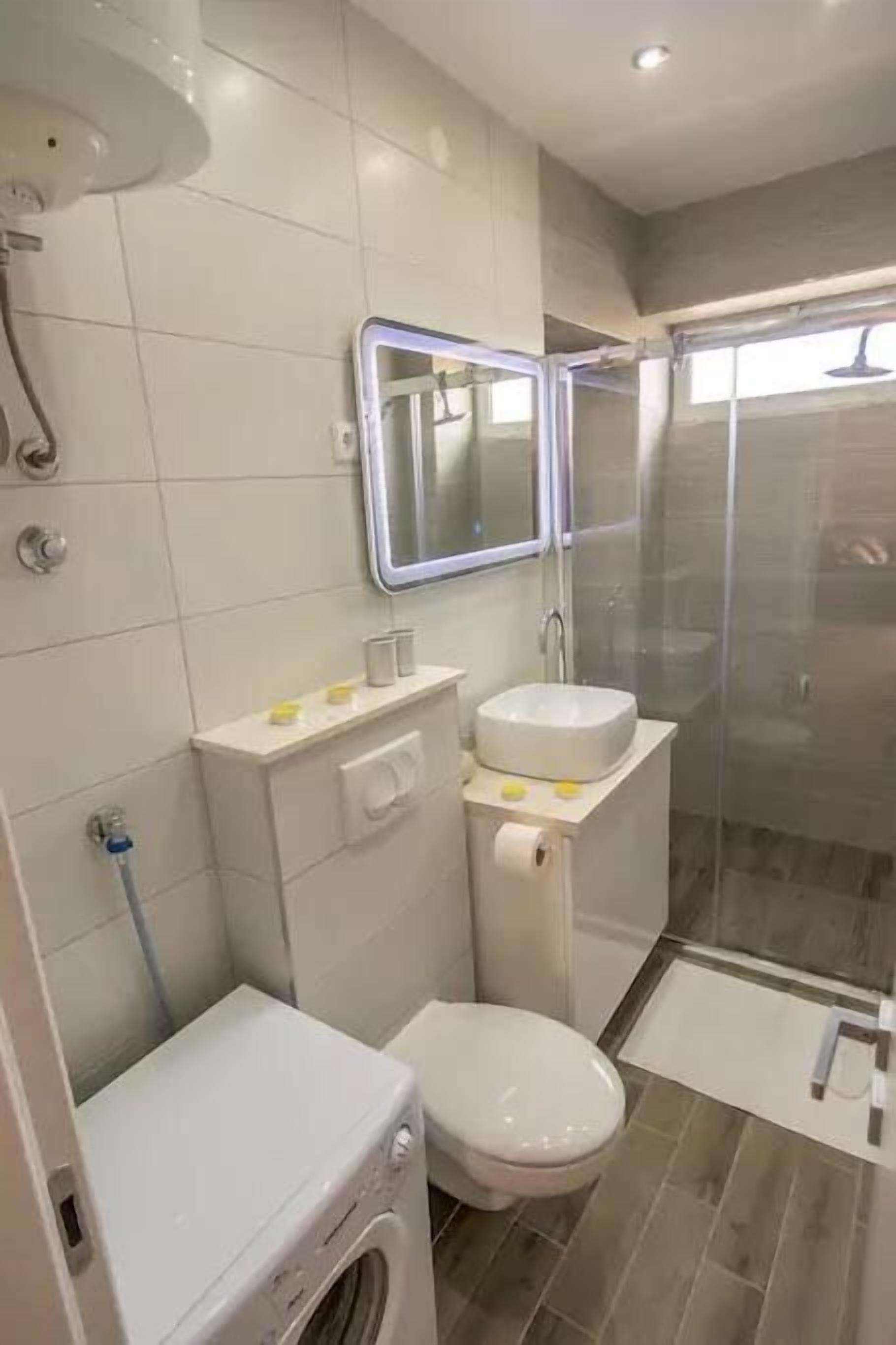 A compact bathroom with a toilet, sink, and shower.
