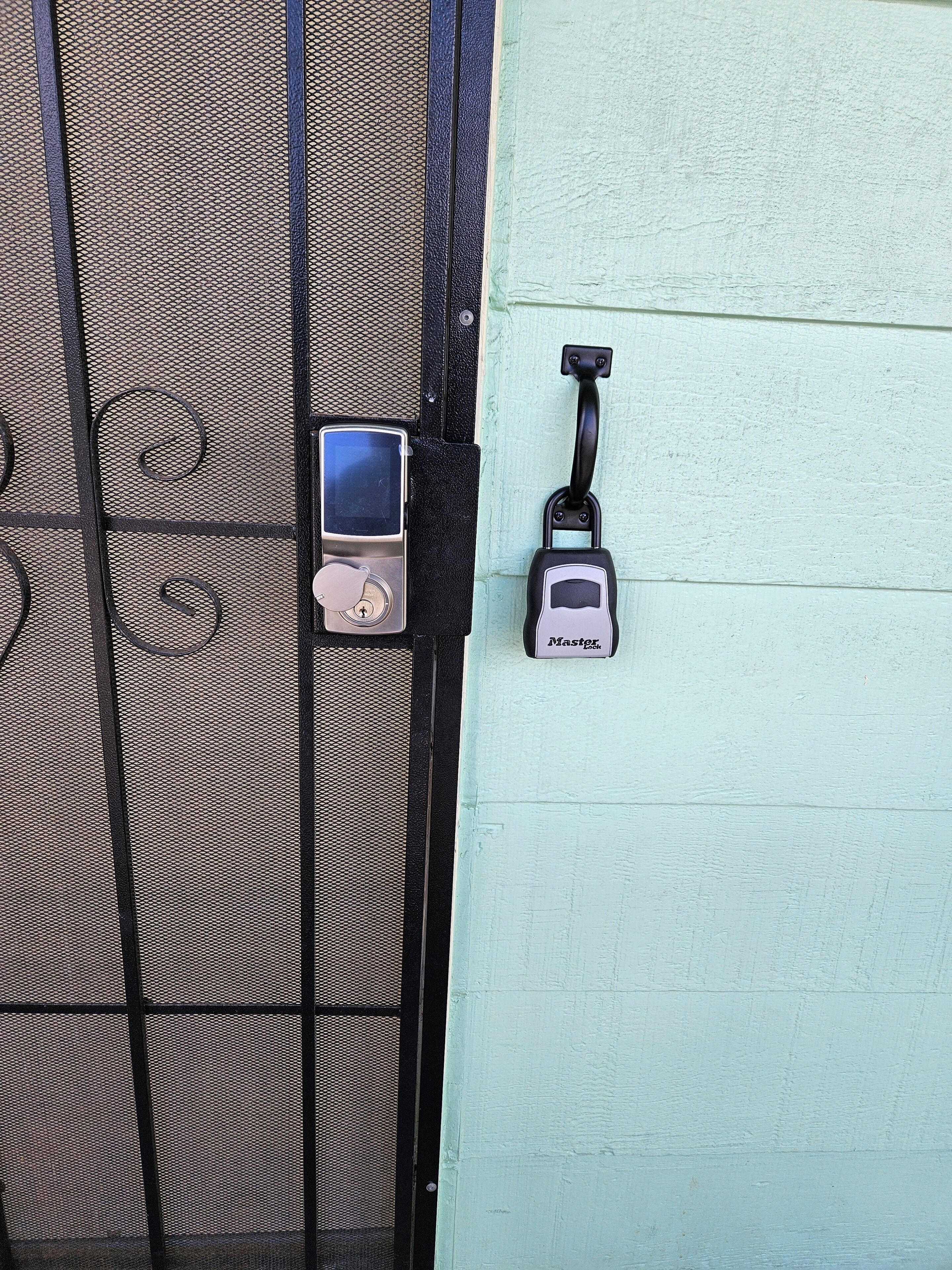A metal gate with a mesh design, a padlock, and a key.