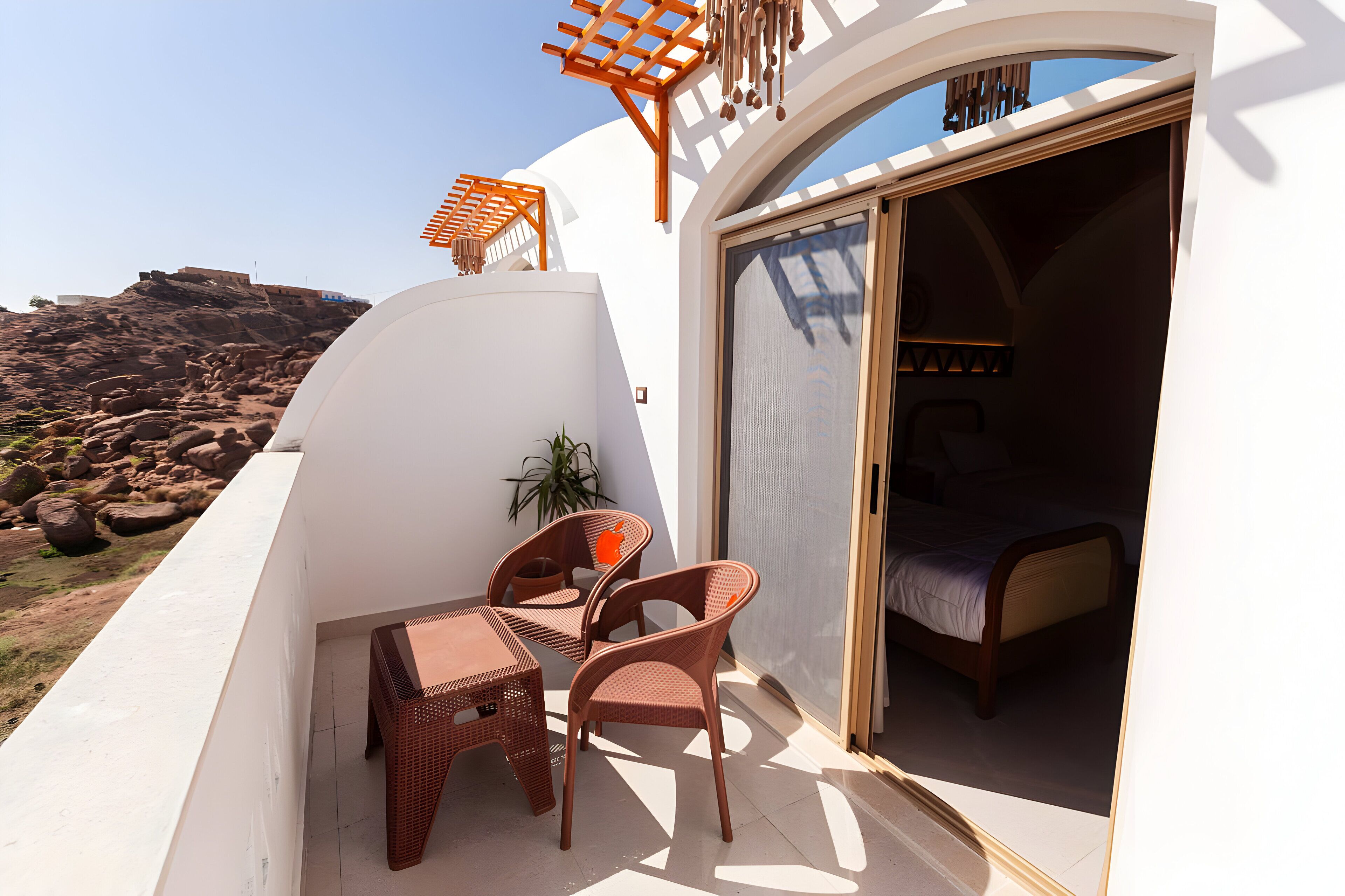 A balcony with wicker furniture, a bed, and a view of rocky terrain.