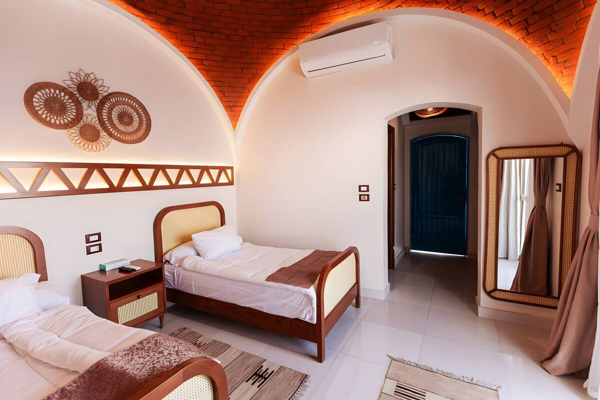Un dormitorio con dos camas, un espejo y una puerta que da a otra habitación.