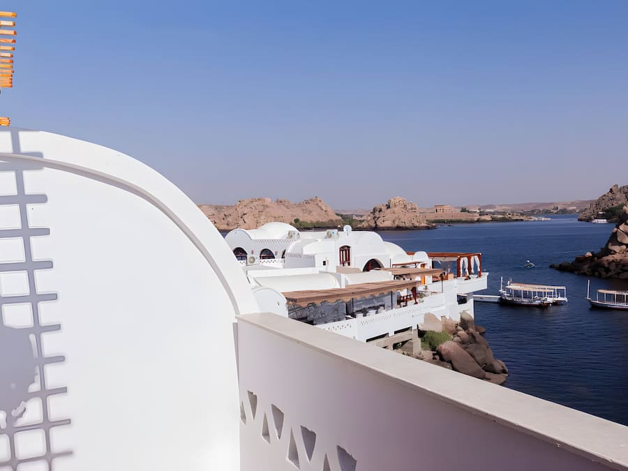 Un hotel costero de arquitectura blanca, con vista al mar y barcos amarrados cerca.