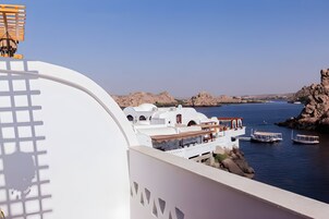 Un hotel costero de arquitectura blanca, con vista al mar y barcos amarrados cerca.